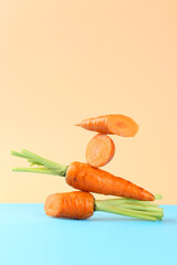 Whole and cut fresh carrots on color background