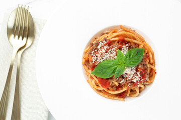 Delicious pasta bolognese with basil and cutlery on table, top view