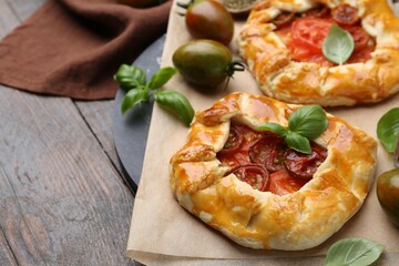 Tasty galettes with tomato and basil on wooden table, closeup