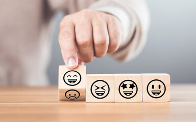 Wooden blocks displaying a sad face transitioning to a happy face, symbolizing a shift from negativity to positivity. Final block turns from sad to happy, highlighting the power of a positive outlook