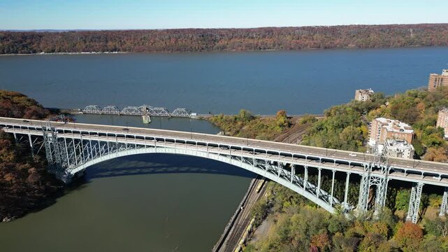 This aerial view captures the Henry Hudson Bridge gracefully arching over the river, connecting the Bronx to Manhattan. Surrounded by lush foliage and scenic water views, the bridge stands as a striki