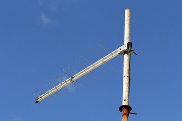 Obraz premium Television antenna mounted on a rusty metal pole against a blue sky background