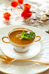 Orange pumpkin and ginger soup served on gold rimmed white fine China plates