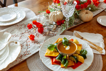 Pumpkin Ravioli with summer squash around a bowl of pumpkin and ginger soup