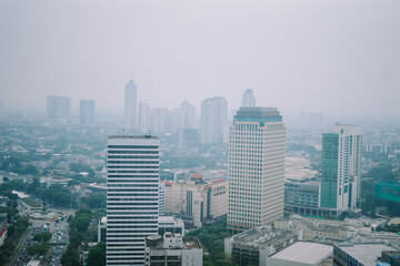 Obraz premium High-rise buildings and a major road in Jakarta city, with visible air pollution creating a hazy urban atmosphere