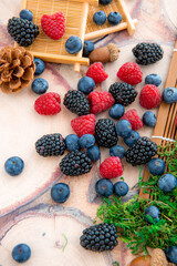 Close-up of fresh blueberry, raspberry, and blackberry with green moss on wood