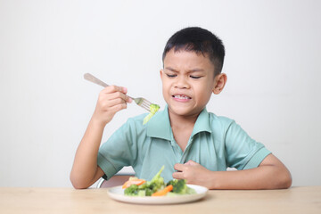 Nutrition healthy eating habits for kids concept. Children do not like to eat vegetables. Little cute boy refuses to eat healthy vegetables.