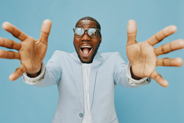 joyful man in stylish suit reaching out, smiling, expressing excitement, against a light blue...