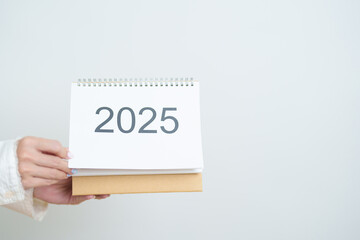 Business woman hand holding and change 2025 Year Calendar on white background table in office. countdown, Happy New Year, Resolution, Year End and New Start and Goals Plan Action Concept