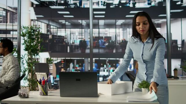 Female employee collecting her office belongings after getting fired, feeling frustrated and depressed over unemployment. Dismissed indian girl leaving her space, career failure. Camera B.
