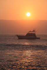 Beach sunrise: orange sky, calm sea, boat, captivating beauty in nature.