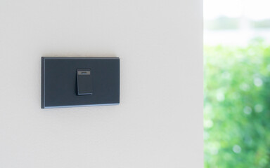 The black light switch on white wall is turned on.