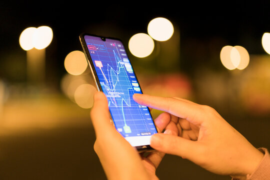 A trader is analyzing financial data on a digital mobile online trading platform.