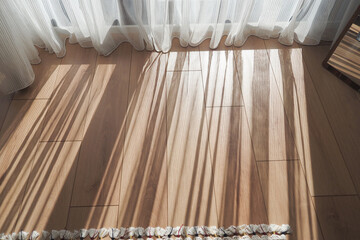 Sunlight on the wooden floor with sheer curtains creates a serene, inviting atmosphere