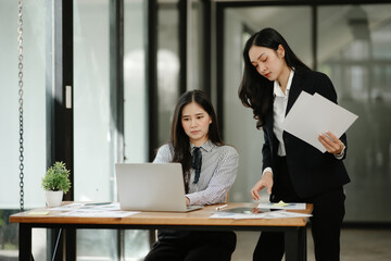 Two business women sitting and working Documents in front of the computer
