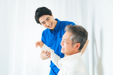 Obraz premium マッサージ、ストレッチ、リハビリ、肩、肩痛、トレーナー、五十肩、治療、関節、患者、笑顔、男性、日本人、高齢者、四十肩、シニア、中高年、お年寄り、老人、ケアスタッフ、ヘルパー、相談、診断、診療、理学療法士、整体、整体師、診察、介護士、介護、肩関節周囲炎、ローテーターカフ損傷、肩峰下滑液包炎、肩こり、加齢、老化、リハビリテーション、インナーマッスル、トレーニング、腱板損傷、肩蜂下インピンジメント症候群