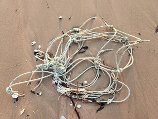 Old thick ship rope thrown out on sand seashore. Plastic and ropes, Coastline pollution. Debris...