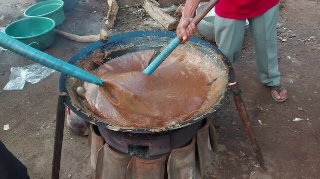 Men make traditional Indonesian food jenang stirred strongly in rhythm. Jenang is a typical Javanese food made from glutinous rice flour, brown sugar and coconut milk which produces a savory and sweet
