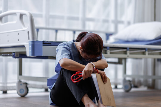 Medical nurse is on bed in hospital sitting down a the hospital corridor in frustration and grief after failure and patient body condition