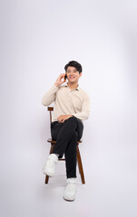 Full body image of a young businessman sitting in a chair using phone  and posing on a white background