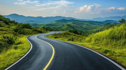 A winding asphalt road curves through a lush green mountain landscape under a bright blue sky with fluffy white clouds.