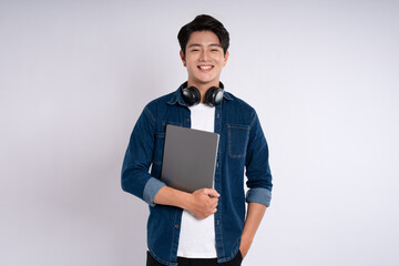 Portrait of Asian male student wearing cable and headphones , using laptop and  posing on white background