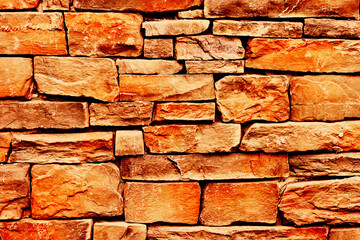 Orange brick wall. Horizontal decorative uneven blocks background. Urban architecture texture. Solid stone pattern. Grunge brickwork structure.