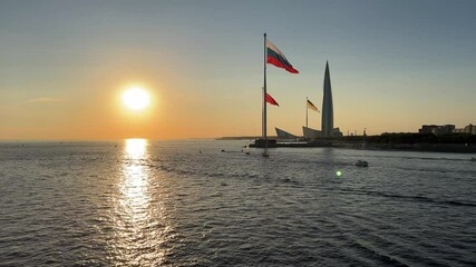 Saint-Petersburg, Russia - September 8, 2024: Sunset. Horizontal 4K video. Setting sun. Flag of USSR, Russian Federation, Russian Empire on shores of Gulf of Finland. Urban view. Reflection in water - Powered by Adobe