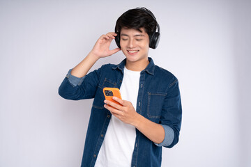 Portrait of young Asian man listen to mucsic and posing on white background
