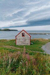 Country barn and gravel road by the ocean on a stormy day with dark brooding clouds by the...
