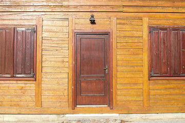 Wooden house facade. Closed shutters. American saloon entrance. Rustic retro architecture wooden doors and windows. Sunlight cottage house. Front home structure. Antique facade. Ancient style design.