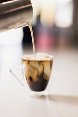 An artisanal glass mug of coffee mixed with milk