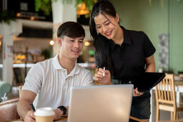 Two positive Asian colleagues are brainstorming together and discussing work.