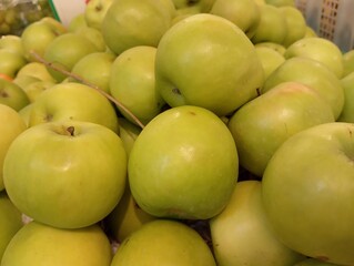 A stack of fresh green apples sits invitingly, their crisp, shiny skin reflecting light.