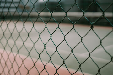 Fototapeta premium Protective wire fence surrounding a tennis court, providing safety and security for players