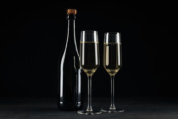 A glass with a bottle of champagne on a black background