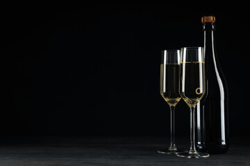 A glass with a bottle of champagne on a black background