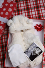 Gift box with newborn clothes ,prenatal ultrasound picture of baby on the red background
