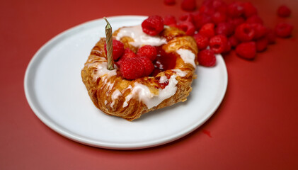 Delicious sweet pastry with raspberry and candles on the white plate and red background 