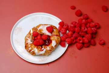 Delicious sweet dessert with raspberry on the white plate and red background with sparkles