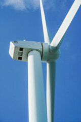 A large wind turbine for generating electricity using the force of the wind installed in an agricultural field against a blue sky.