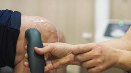 Close-up of a physiotherapy session showing a professional applying ultrasound treatment to a patient's knee. Concept of rehabilitation, medical care, and physical therapy.