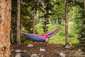 Colorful hammock tied between trees in a forest with shoes underneath