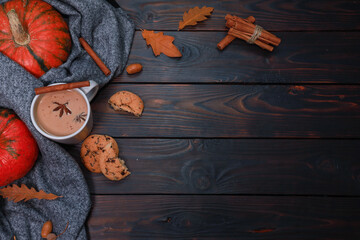 Pumpkin spicy latte, autumn hot drink, scarf and spices on dark brown wooden table. Cozy decoration for autumn coffee shop concept, thanksgiving celebration flat lay wit h copy space