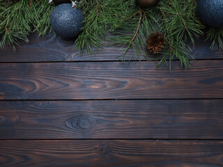 Festive Christmas wooden background with copy space, fir tree branches and blue Xmas baubles. New year celebration, winter holiday concept. Top view of flat lay