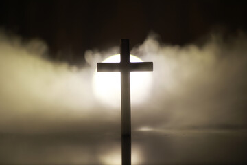 Christian Cross Silhouette with Radiant Light and Misty Background in Dark Surroundings