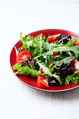  Salad with fresh tomatoes and arugula on a bright wooden background. Close up. Copy space.