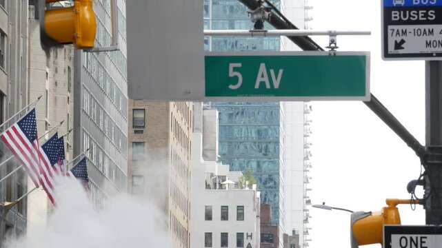 Fifth avenue, 5 ave road sign, Manhattan midtown architecture, New York City 5th av street corner. Traffic crossroad signage, USA. American flag, United States. Steam vapor stack, hot vapour smoke.