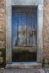 Dettaglio di una porta di legno dipinta di blu sulla facciata di una casa abbandonata nel borgo di Erto, nei pressi della diga del Vajont 