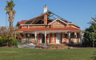 An abandoned stone farm house with a broken and missing corrugated iron roof and a chimney sticking...